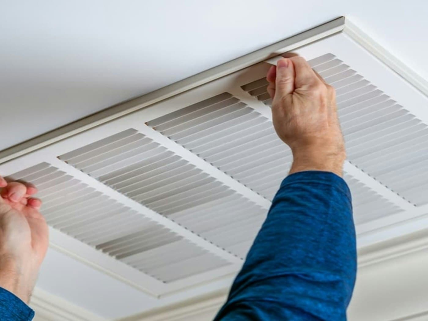 Ceiling air conditioning vent grille being opened for duct cleaning