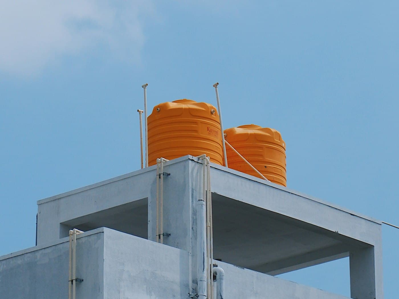 Rooftop water storage tanks on a building against a blue sky