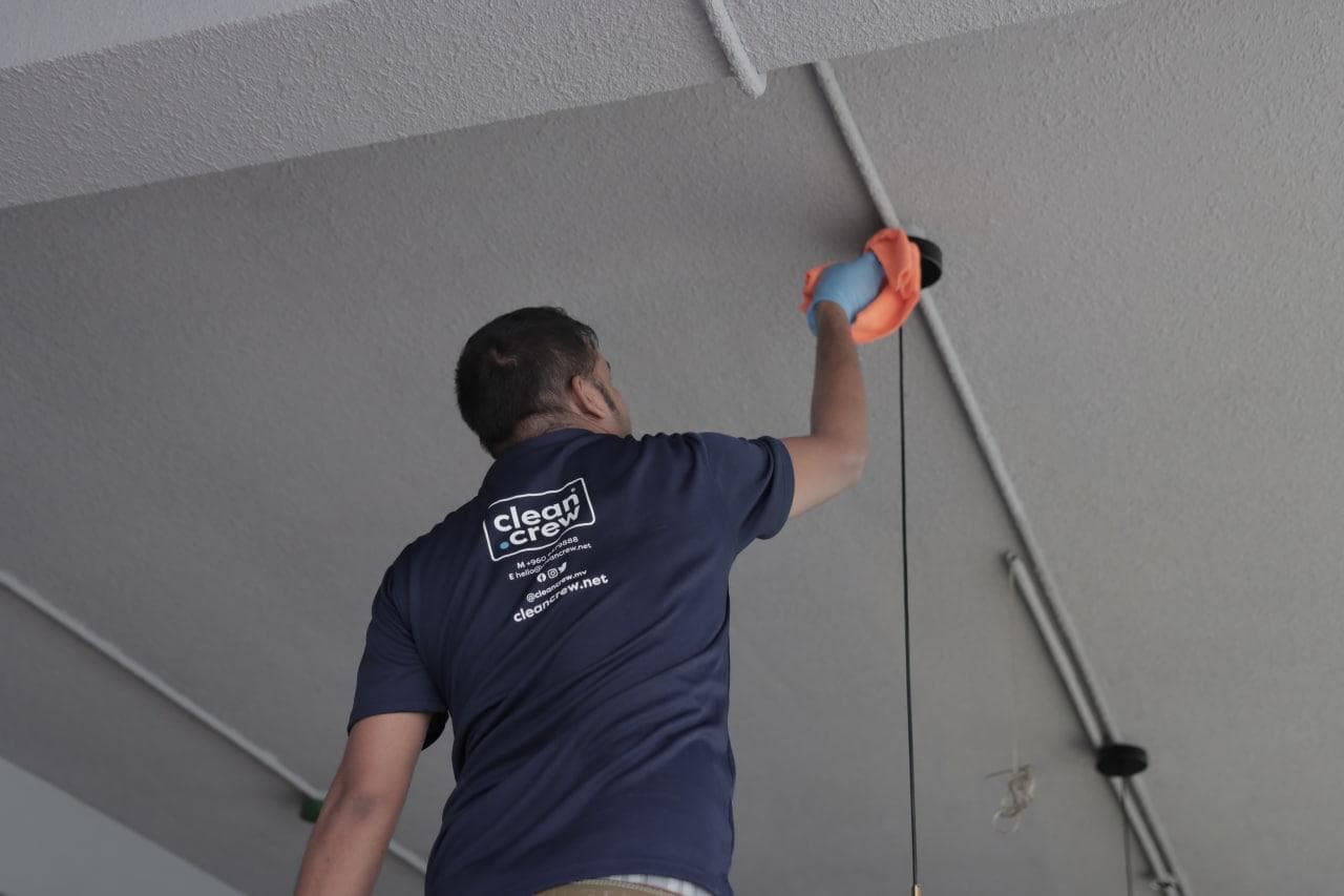 Clean Crew technician dusting exposed ceiling pipework