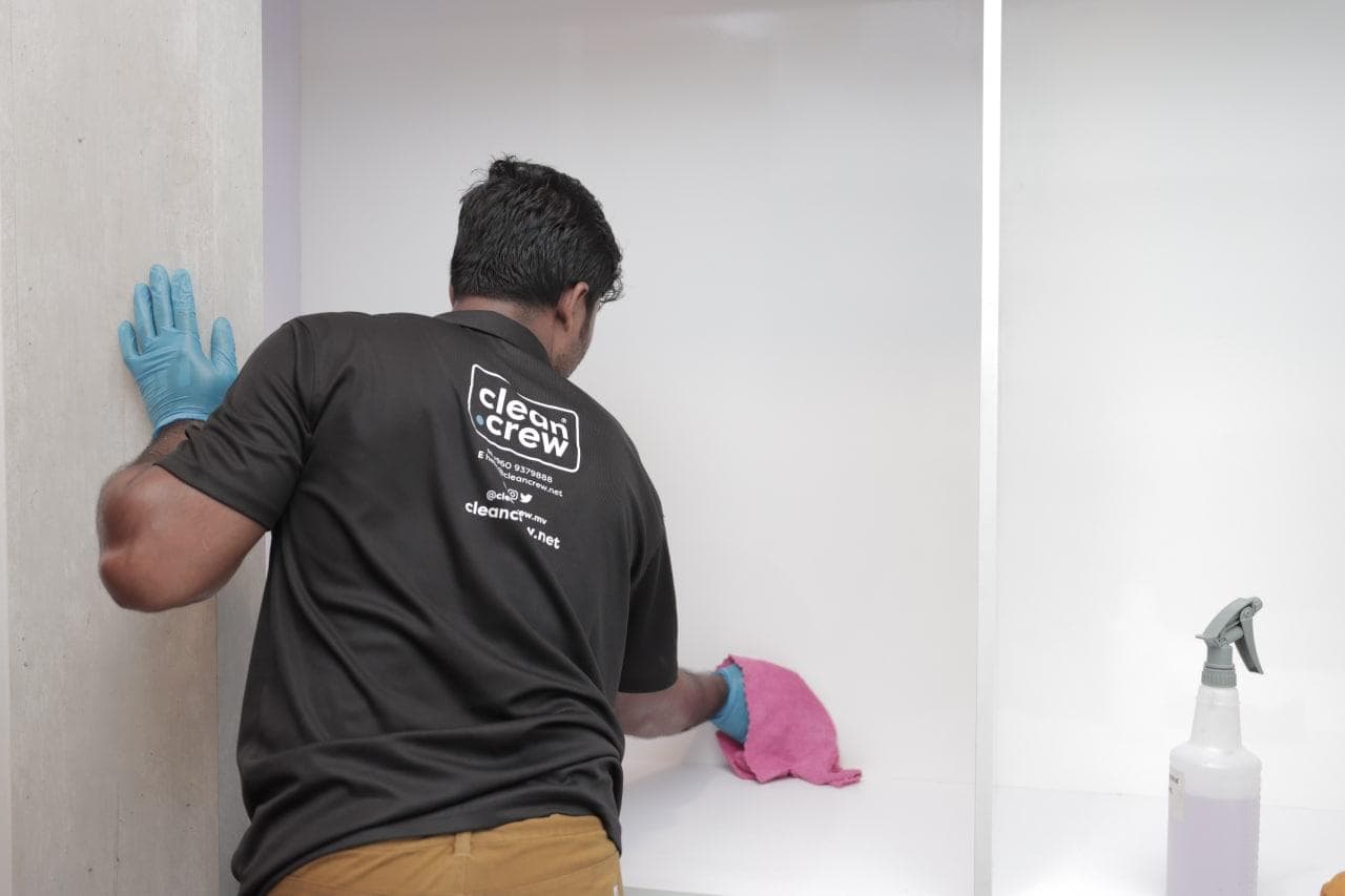 Clean Crew technician in gloves wiping down a wall during a deep clean